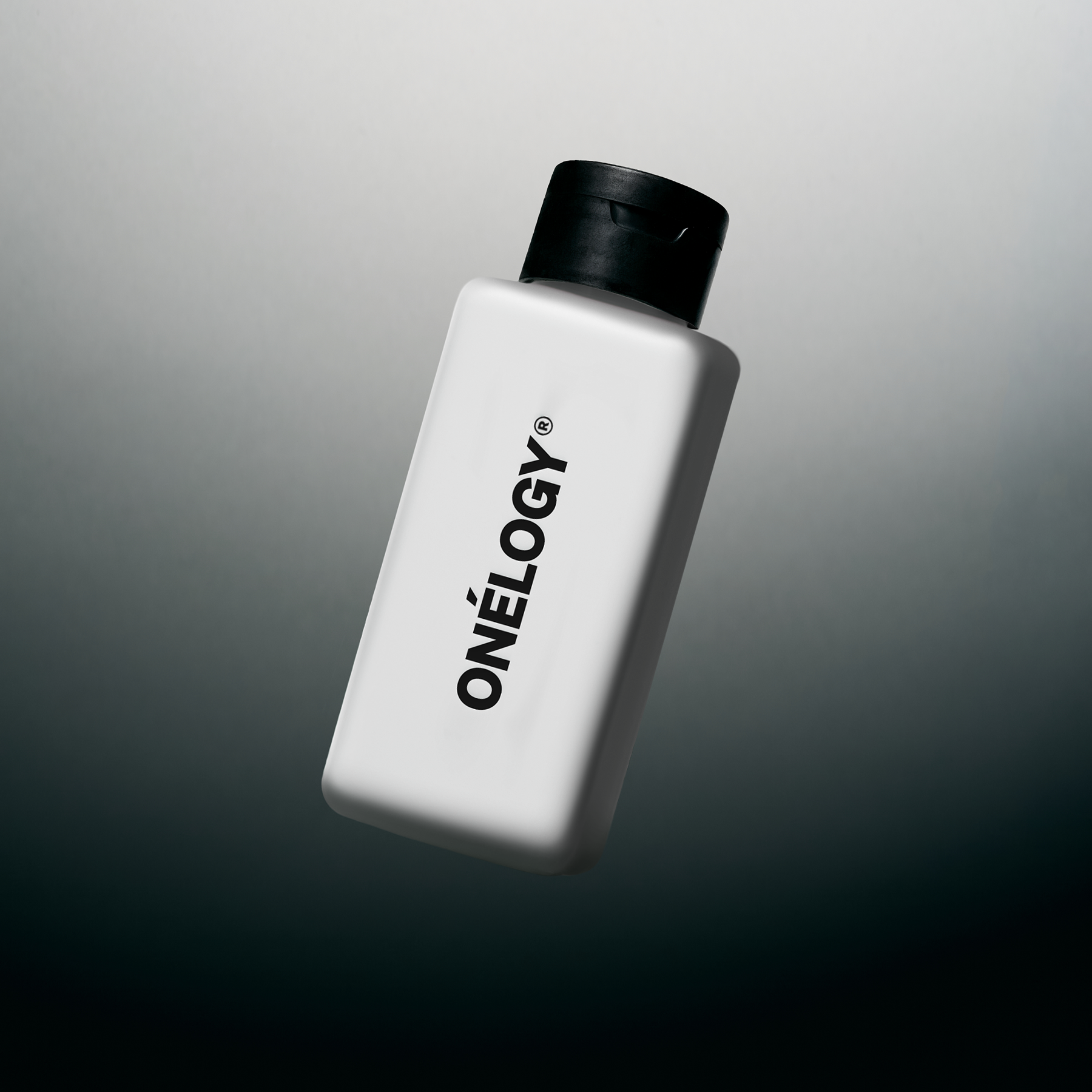 White bottle with black cap labeled 'ONéLOGY' on a gradient gray background