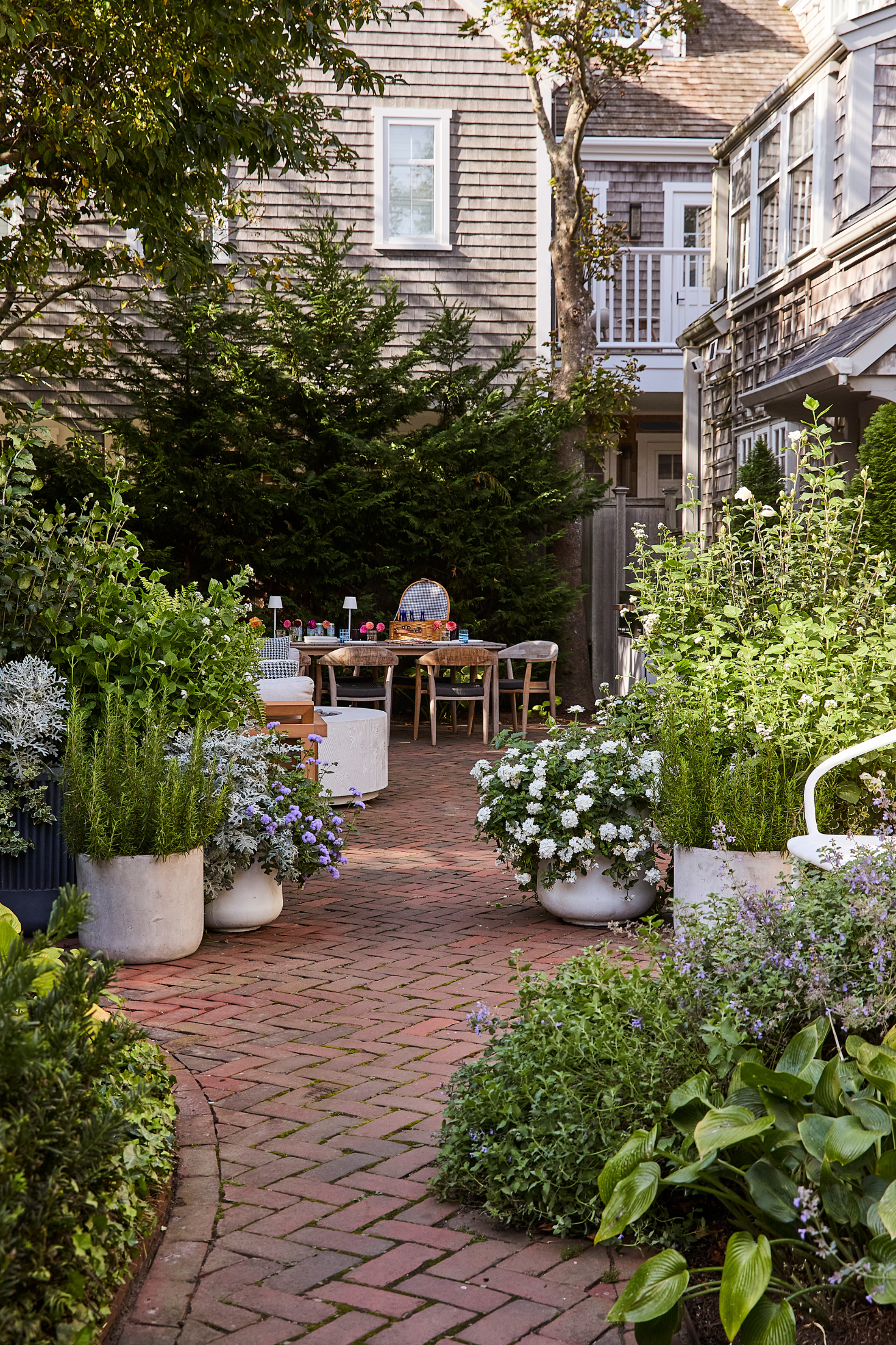 Backyard garden with potted plants and a brick pathway leading to a wooden deck.