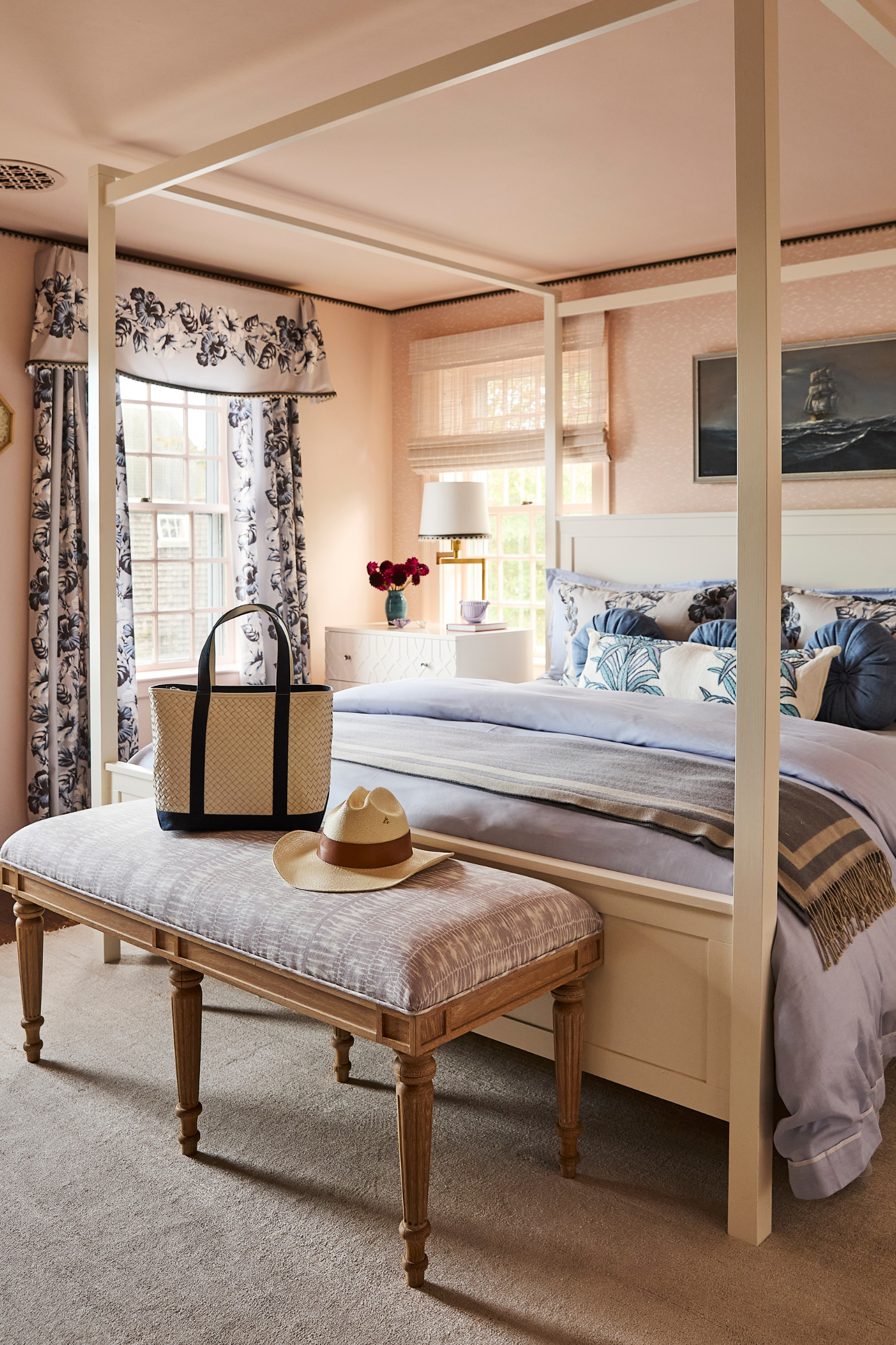 Neatly decorated bedroom with a four-poster bed, bench, and floral curtains.