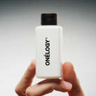 Hand holding a Oneley product bottle against a gray background