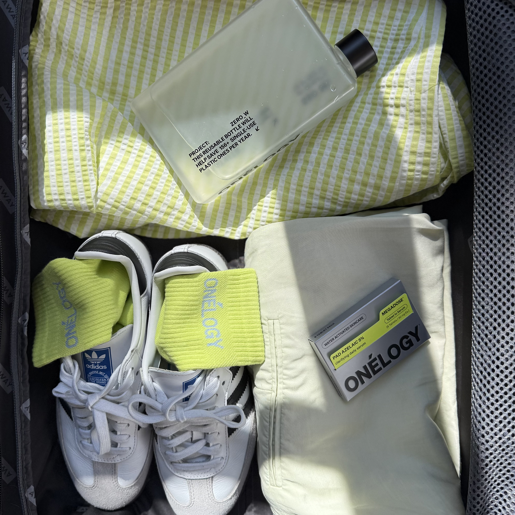 Open suitcase with yellow checkered towel, white sneakers, yellow socks, and grooming products.