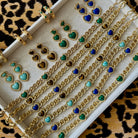 Gold jewelry set with green and blue heart-shaped stones on a leopard print background
