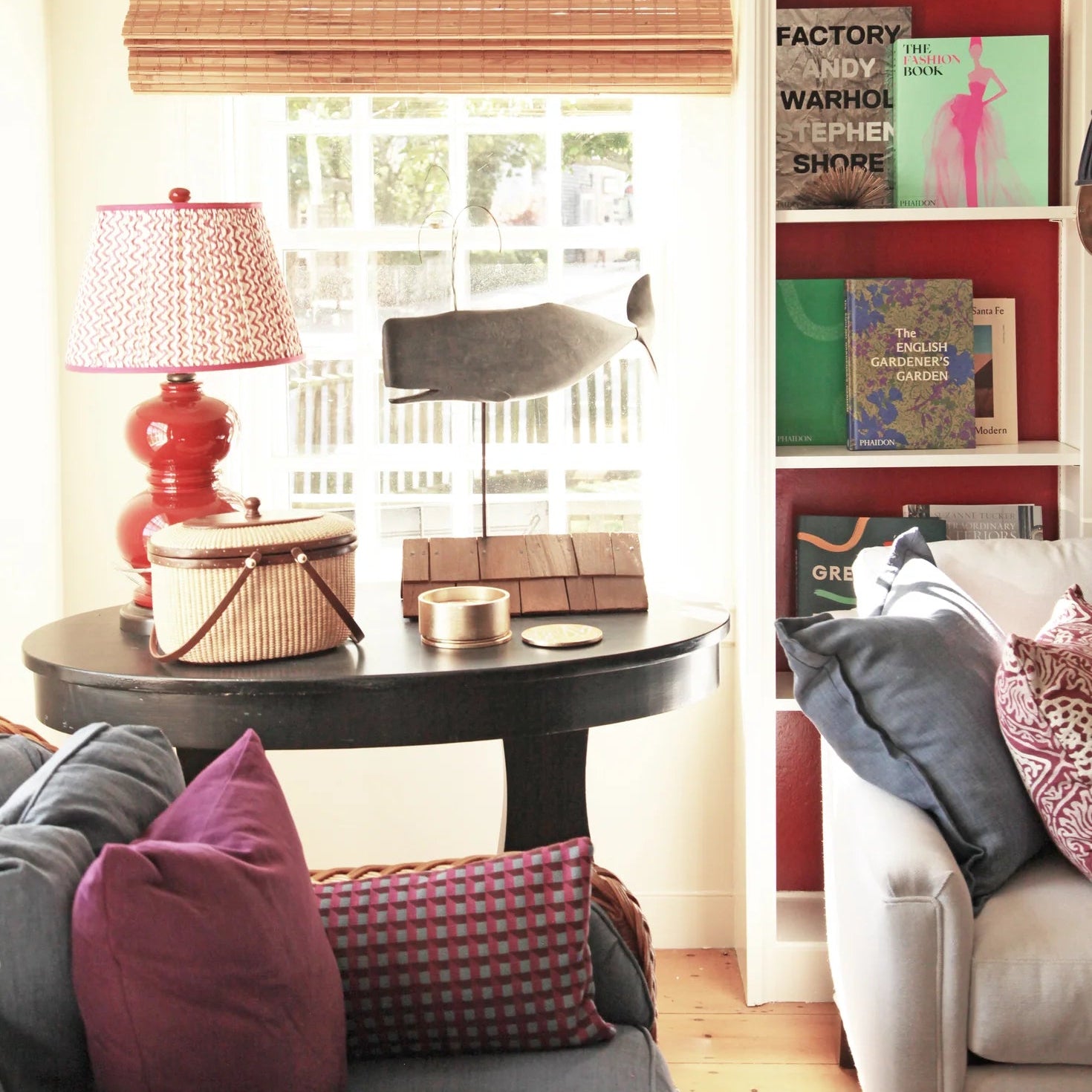 Living room with a bookshelf, table, and couch with pillows.