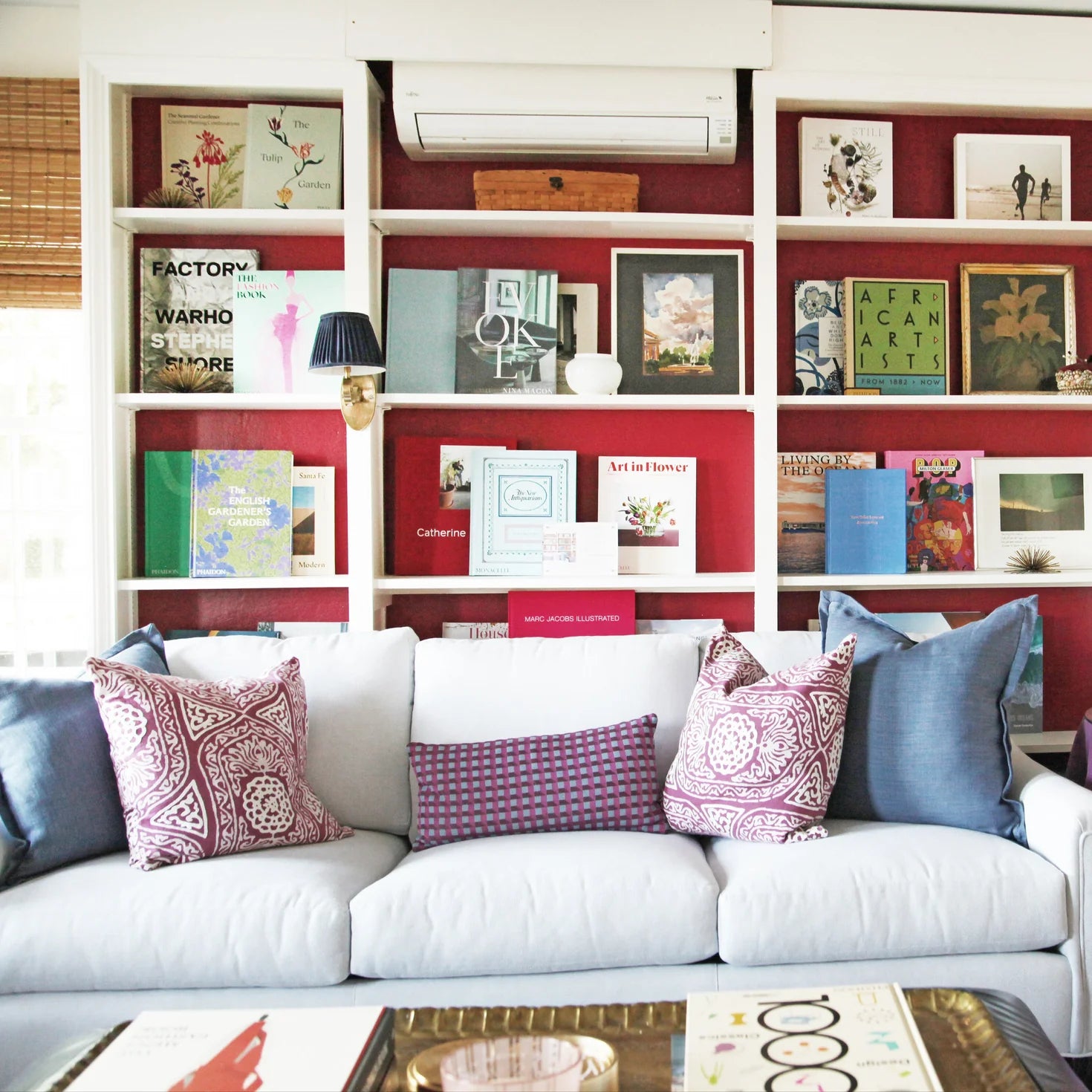 White sofa with patterned cushions in a room with a bookshelf displaying books and decorative items.