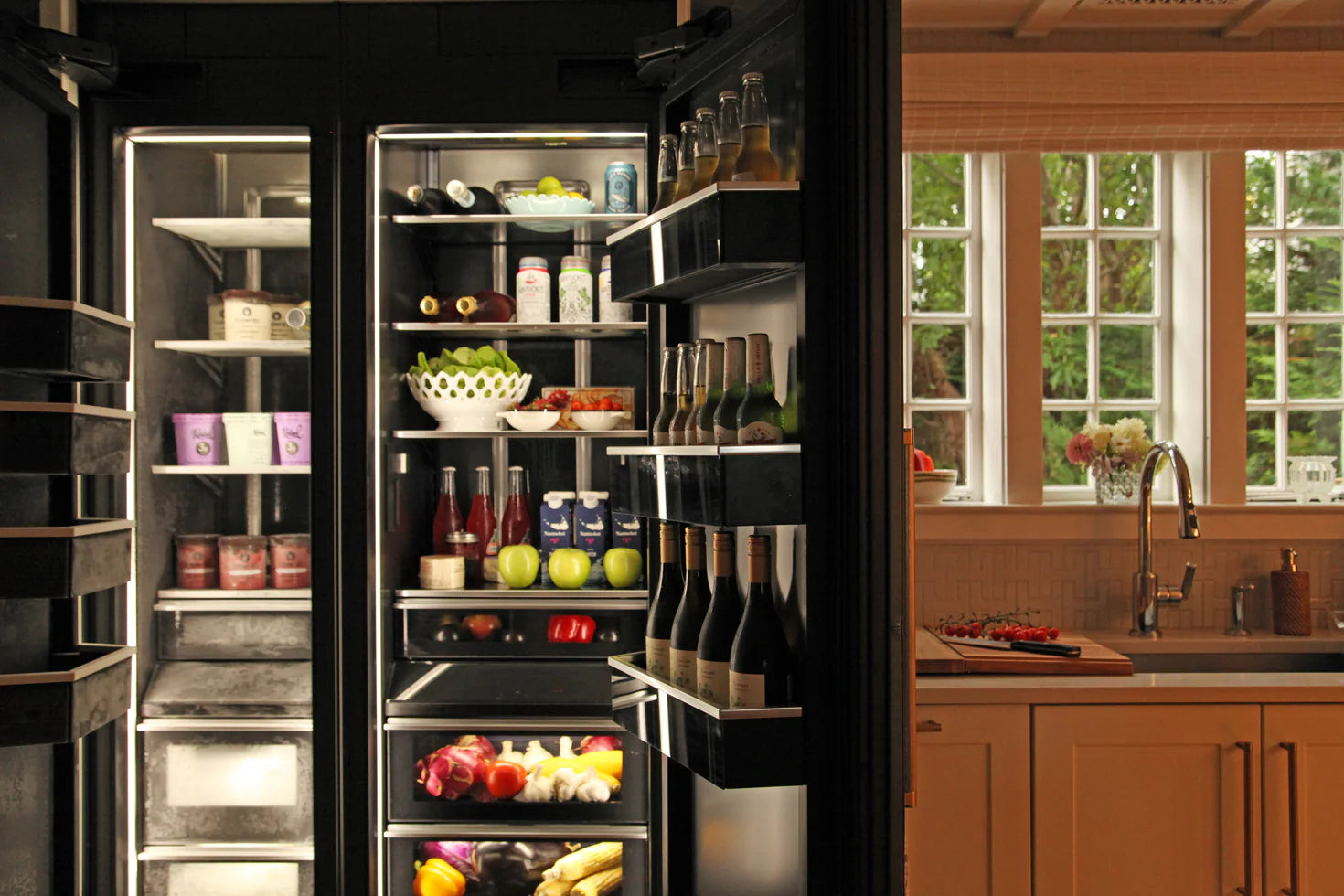 Modern kitchen with a refrigerator stocked with food and drinks.