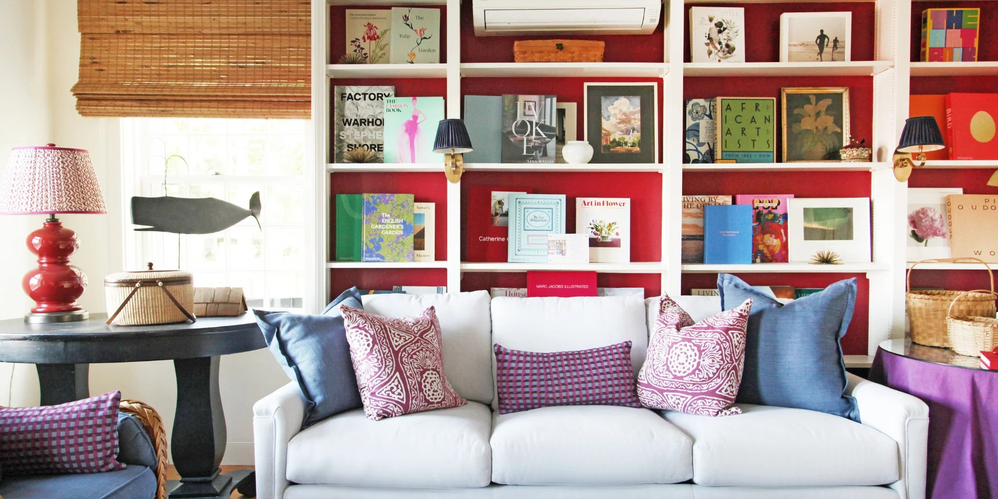 Living room with a white sofa, colorful pillows, and a bookshelf filled with books and decor items.