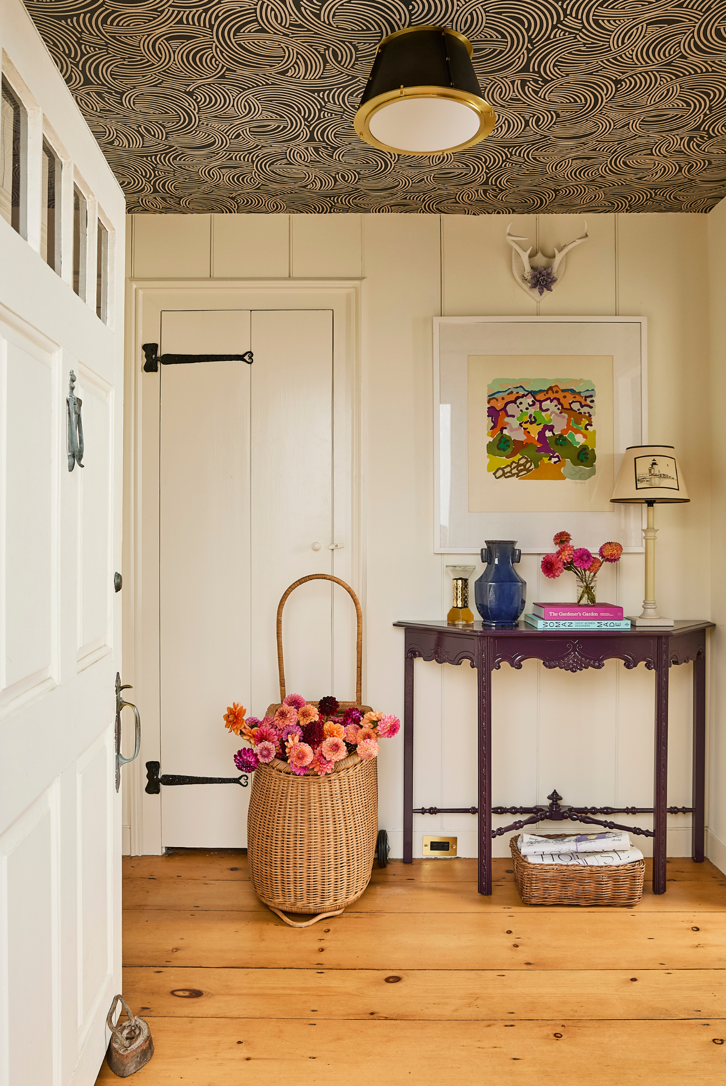 Bright entryway with wood floors, patterned ceiling, and a styled console table with florals and decorative accents.