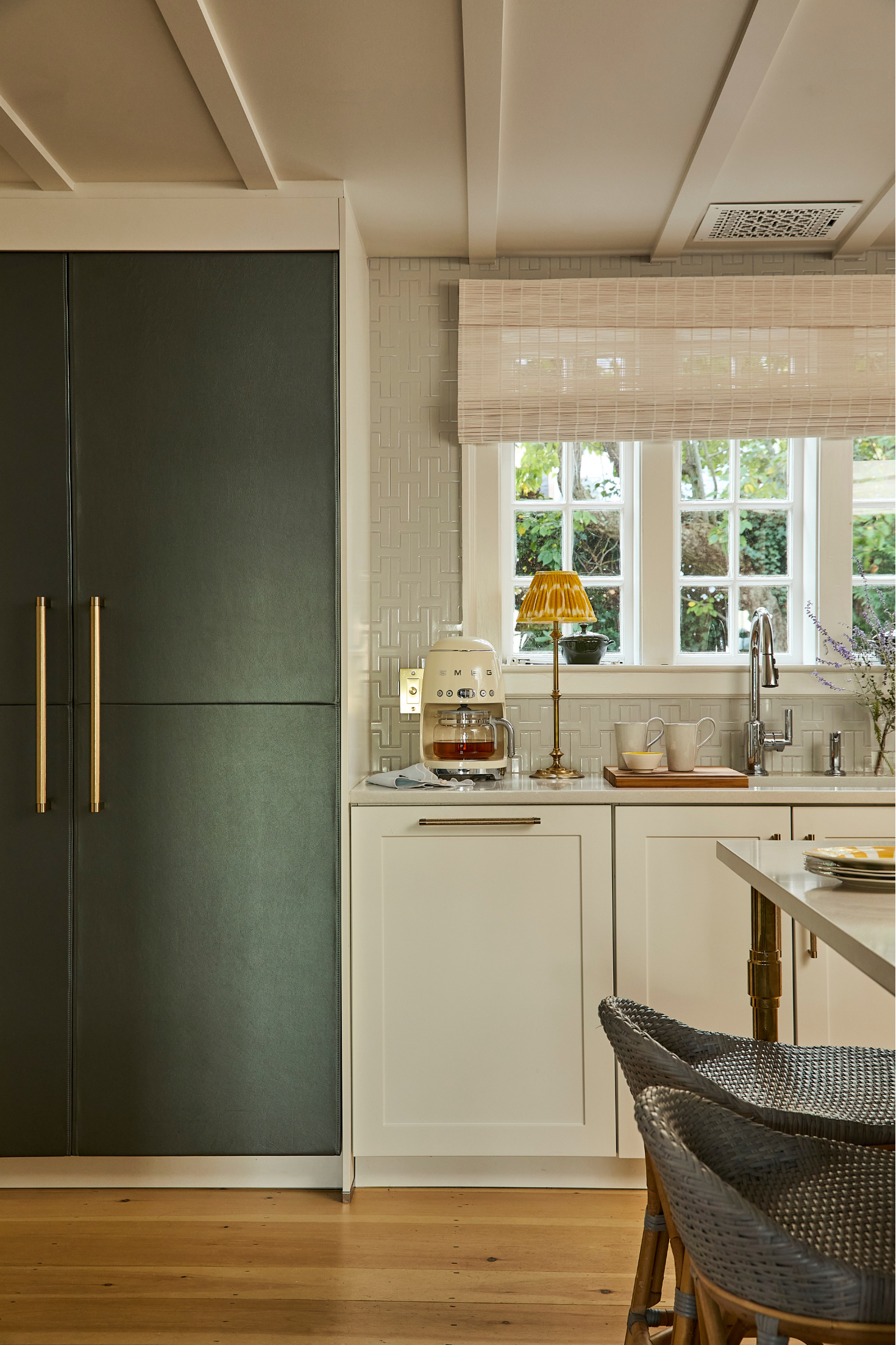 Modern kitchen with green refrigerator, white cabinets, and a window view.