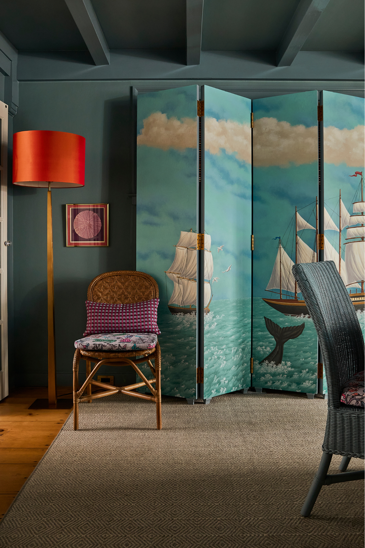 Room with decorative screen featuring ship designs, chair, and lamp.